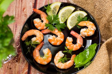 Limon dilimli haşlanmış karideslerin yakın çekimi, ahşap bir masada..