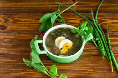 Ev yapımı yeşil pancar çorbası. Kaynamış yumurta ve koyu ahşap bir masada taze kuşbaşı..