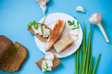 Geleneksel Ukrayna yemeği. Mavi arka planda domuz yağı ve yeşillikler..