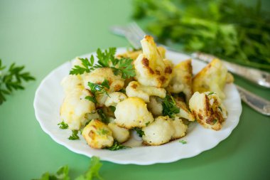 Yeşil arka planda baharat ve otlarla kızartılmış karnabahar..