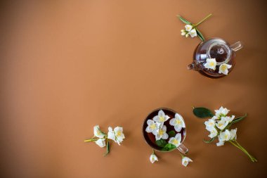 Kahverengi arka planda yeşil çay ve yasemin çiçekli çay kompozisyonu.