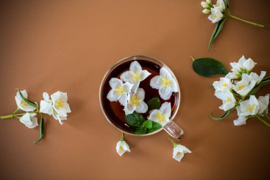 Kahverengi arka planda yasemin çiçekli demlenmiş yeşil çay..