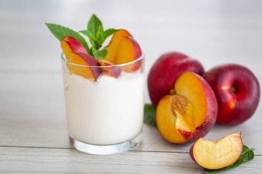 Hafif ahşap üzerinde ev yapımı yoğurdun içinde olgun sulu nektarinler..