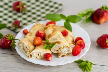 Çilekli leziz krepler ve ahşap masada yumuşak süzme peynir..