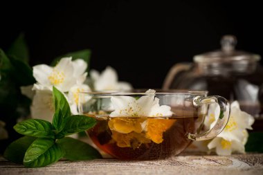 Siyah arka planda yasemin çiçekli rahatlatıcı çay.