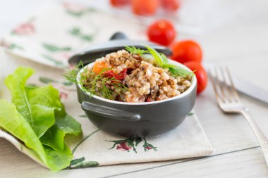 Tahta bir masada seramik kasede sebzeli haşlanmış karabuğday..