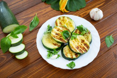 Koyu ahşap arka planda ızgara kabak dilimleri..