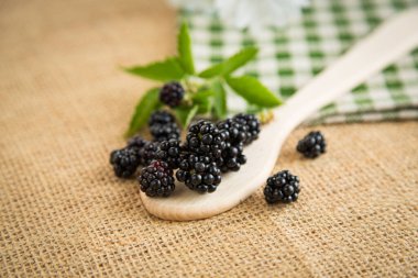 Yaprak ve kaşıkla olgun böğürtlenleri yakın çekim.