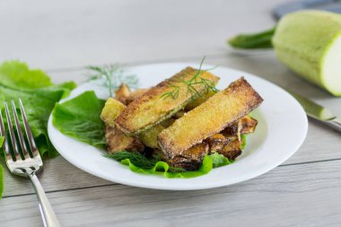 Kızarmış kabak dilimleri ve salata yeşili..