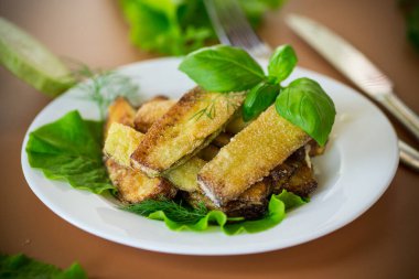 Kahverengi arka planda beyaz tabakta ev yapımı kızarmış kabak..