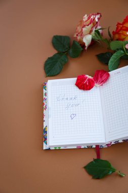 Çiçekler, köpüklü kahve ve boş sayfalarla dolu rahat bir masa..