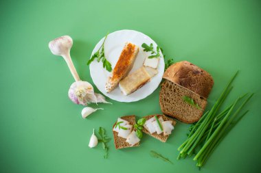 Yeşil zemin üzerinde domuz yağı ve yeşillik bulunan geleneksel Ukrayna yemeği.