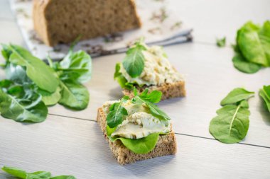 Ringa salçalı sandviç ve açık ahşap bir masada yeşillikler..