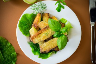 Kahverengi arka planda salata yeşili kızarmış kabak dilimleri..