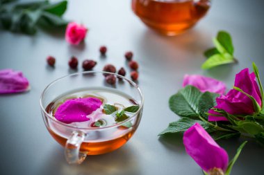 Bitki kökü ve nane çayı bir fincanda ve çaydanlık yukarıdan.