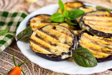 Beyaz bir tabakta sulu patlıcan dilimleri, sade servis..