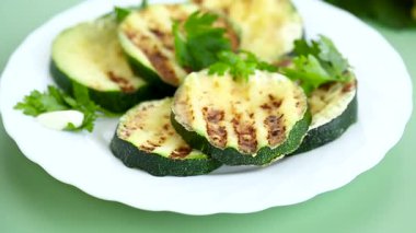 Izgara kabak dilimleri yeşil arka planda bir tabakta