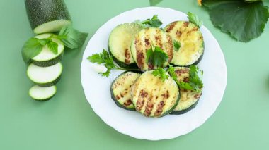 Izgara kabak dilimleri yeşil arka planda bir tabakta