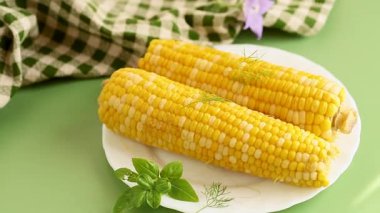 Kaynamış mısır ve otlar yeşil arka planda minimalizm