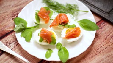Masada kırmızı balık ve otlarla süslenmiş yumurtalar.