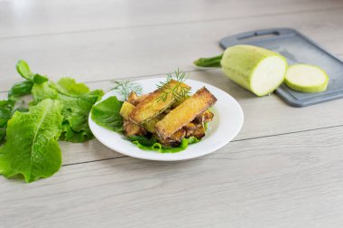 Kızarmış kabak dilimleri ve salata yeşili..