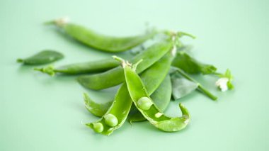Yeşil arkaplanda taze bezelye ve yapraklar.