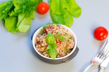 Gri arka planda sebzeli karabuğday yemeği.