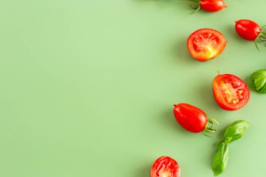 Pastel yüzeyine fesleğenle saçılmış taze kırmızı domatesler..