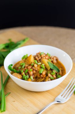 Sebze yahnisi, et ve patatesle masada beyaz bir kasede..