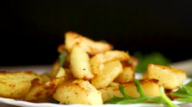 Siyah arka planda sarımsaklı ve otlu fırında patates..