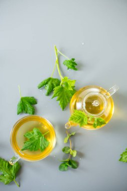 Cam çaydanlıkta çay ve fincanda frenk üzümü ve nane yaprağı..