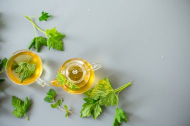 Cam çaydanlıkta çay ve fincanda frenk üzümü ve nane yaprağı..