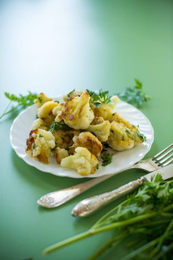 Yeşil arka planda baharat ve otlarla kızartılmış karnabahar..