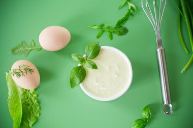 Yeşil arka planda otlu ve yumurtalı ev yapımı mayonez..