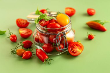 Yeşil arka planda fesleğenli çeşitli kiraz domatesleri..