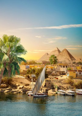 Aswan 'da gün batımında Nil Nehri ve tekneler ve piramitler