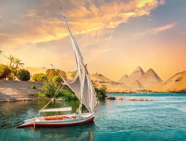 尼罗河和日落时分在阿斯旺和金字塔中的船只 — 图库照片