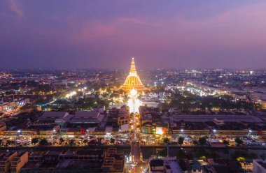Phra Pathom Chedi, Nakhon Pathom, Tayland 'da gün batımı bölgesinde büyük bir altın pagoda bulunmaktadır. Ölçüm halka açıklandı. Otomobil parklarıyla dolu bir kavşağın Tayland hava manzarası. Harika.
