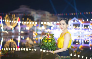 Loy Krathong Geleneksel Festivali, Tayland 'daki Loy Krathong kutlamalarında dolunay gecesi su tanrıçası için güzel bir Taylandlı kadın Krathong süsleme yaprağı tutuyor..