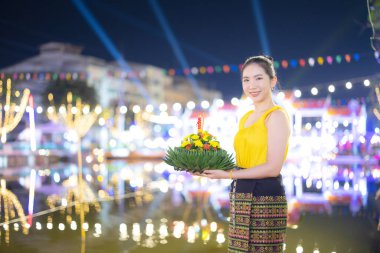 Loy Krathong Geleneksel Festivali, Tayland 'daki Loy Krathong kutlamalarında dolunay gecesi su tanrıçası için güzel bir Taylandlı kadın Krathong süsleme yaprağı tutuyor..