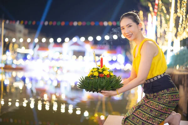 stock image Loy Krathong Traditional Festival, A beautiful Thai woman holds a Krathong ornamental form banana leafs in Loy Krathong celebrations in Thailand for the goddess of water on a full moon night.