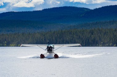 Kanada 'nın Yukon Bölgesi' ndeki Boreal Forest Taiga 'daki ıssız bir göle iniş yapan yüzen uçak.
