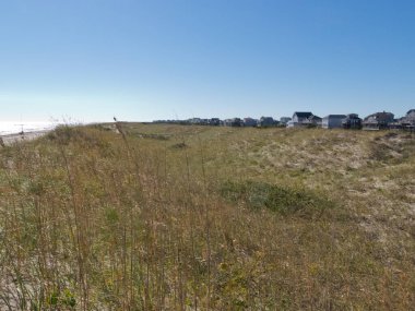 Düşük kum tepeleri ve Outer Banks, OBX, North Carolina, NC, ABD 'deki Hatteras Adası' ndaki kumlu plajların arkasındaki tatil evleri köyü.