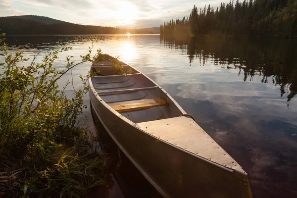 カナダのユーコン準州の人里離れた荒野にある美しいフランス人の湖の岸に縛り付けられたカヌー 湖を囲む北半球の森林タイガの上の日没 — ストック写真