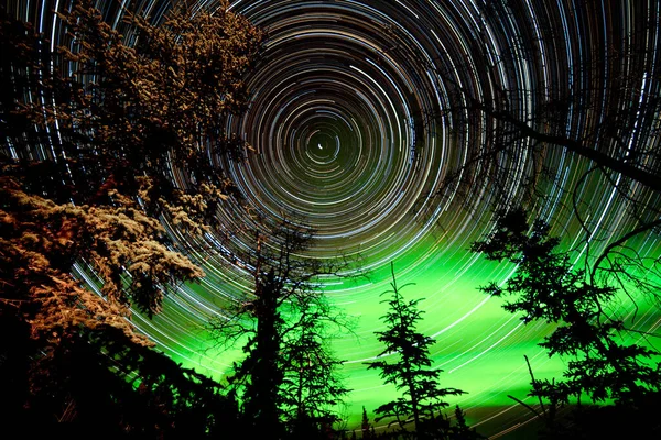 カナダ ユーコン準州の北半球の森やタイガの上にオーロラやオーロラの緑輝くディスプレイを持つ天体写真の星の道 — ストック写真