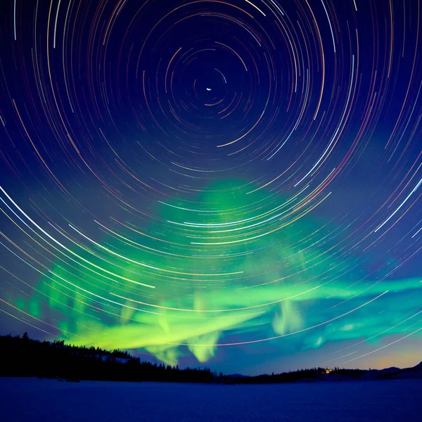 カナダ ユーコン準州のオーロラやオーロラの緑輝くディスプレイと夜明けの亀裂で天体写真の星のトレイル — ストック写真