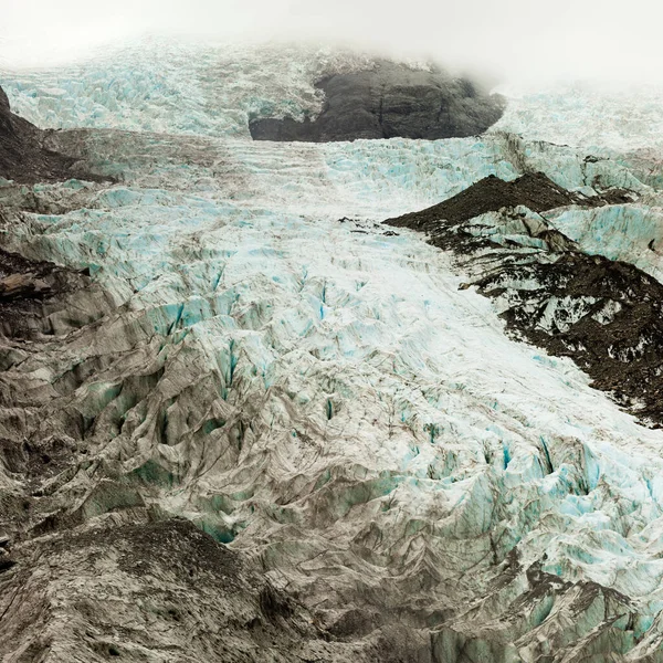由于全球变暖 部分隐藏在云层中的高山冰原在陡峭的斜坡上迅速融化 形成了一个由深谷组成的迷宫 — 图库照片
