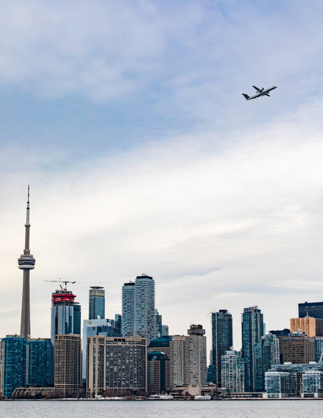 ТОРОНТО, Калифорния, DEC 17, 2017: Самолеты, стартующие из городского аэропорта Торонто с горизонтом центра города, включая башню CN 17 декабря 2017 года в Торонто, Онтарио, штат Огайо, Канада