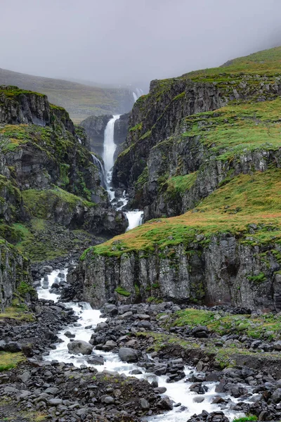 在冰岛东部的Reydarfjordur附近的贫瘠的山边景观中 一个没有名字的小瀑布蜿蜒而过 — 图库照片
