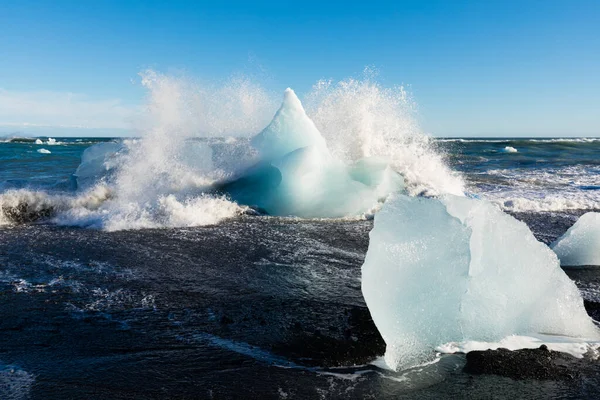 冲刷在欧洲伊利诺斯州Jokulsarlon冰川泻湖附近的钻石海滩上的海浪冲撞到冰块上 — 图库照片